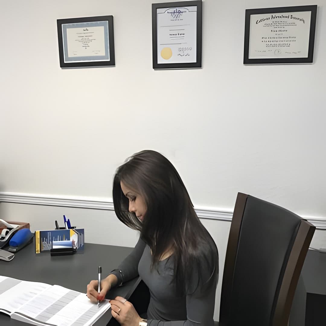 Ferangiz Akhmedova, owner and notary public, working at her desk beneath her framed credentials